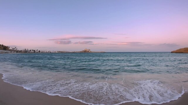 Panorama: Quiet sandy beach at dusk in Monastir, Tunisia, with gentle waves, pastel sky, and soft evening light over the Mediterranean coast, creating a calm travel and lifestyle atmosphere
