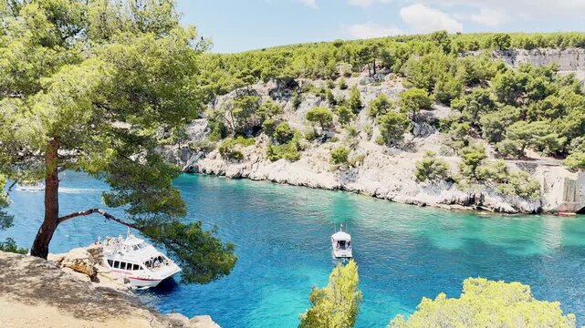 Calanque de Port Miou bay seen from the sea with lush vegetation and tourist boats entering the inlet to admire scenic views, turquoise Mediterranean water on the French Riviera, near Cassis, France.