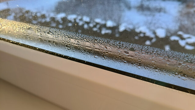 Condensation and water droplets on plastic window frame. Concept of home energy efficiency, ventilation problems, and humidity control.