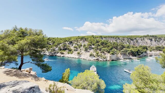 Calanque de Port Miou bay seen from the sea with lush vegetation and tourist boats entering the inlet to admire scenic views, turquoise Mediterranean water on the French Riviera, near Cassis, France.