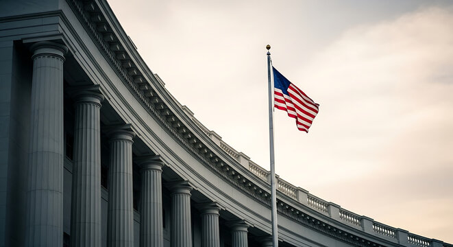 The American flag proudly waves on a flagpole in front of a grand classical building with large columns, under a cloudy sky.