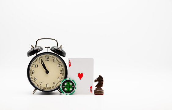 Retro alarm clock showing 23:55 o'clock, chess knight, ace card and casino chip.