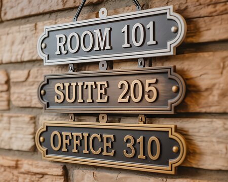 Stacked room signs for room 101 suite 205 and office 310 on a brick wall