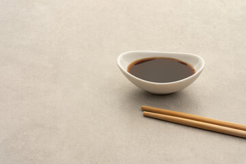 Sauce bowl with soy sauce and chopsticks on a gray stone background