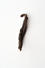 Fototapeta premium Single dried premium Chinese tea leaf sprout with golden fuzz isolated on white background. High-quality loose leaf tea macro photography.