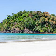 Obraz premium Tropical beach at Koh Tarutao, Thailand. Clear blue water and lush green forest. Sandy shoreline with calm sea. Ao Pantai Melaka in the Andaman Sea.