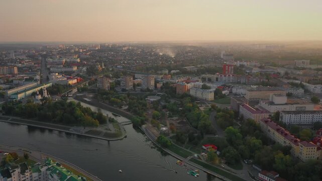 Aerial evening view of Orel city in Russia with river, Strelka, main buildings, churches and roads. Beautiful cityscape with lights reflecting on water at sunset, showing urban architecture, skyline.