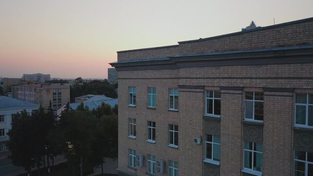 Aerial evening view of Orel city in Russia with river, Strelka, main buildings, churches and roads. Beautiful cityscape with lights reflecting on water at sunset, showing urban architecture, skyline.