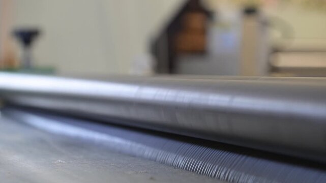 Rotating shafts of an industrial laminator in close-up in a printing house. Mechanics of rotation of metal shafts