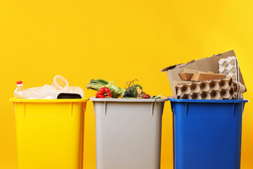 Garbage in trash bins on orange background, closeup. Waste sorting