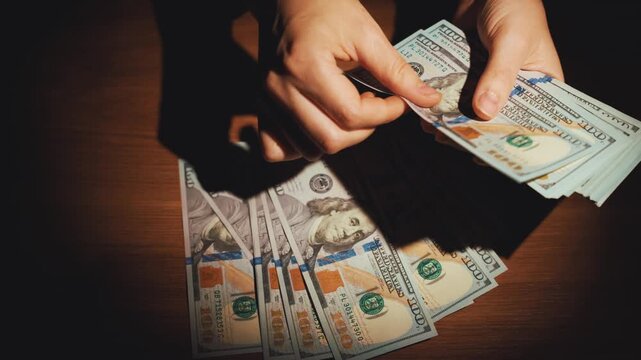 shadow silhouette person counting money, close-up hands holding fan of dollar bills. Concept high taxes. fraud counts cash for profit money laundering investment scam bribe corruption. night dark room