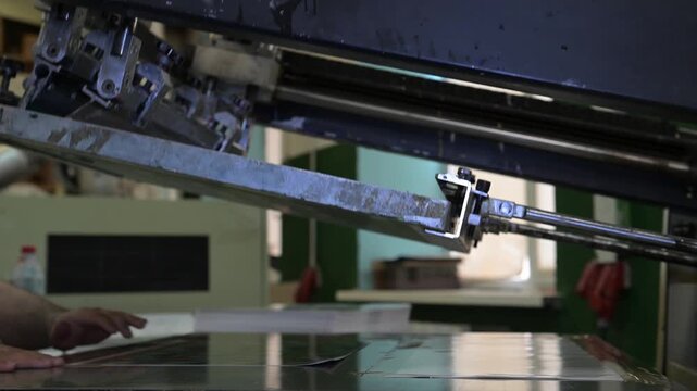 The process of silkscreen printing on a printing press in the production room of the printing house.
