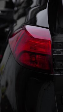 Flashing yellow turn signal and hazard warning light on the taillight of a black car. Modern black car, emergency stop, turn, technical diagnostics