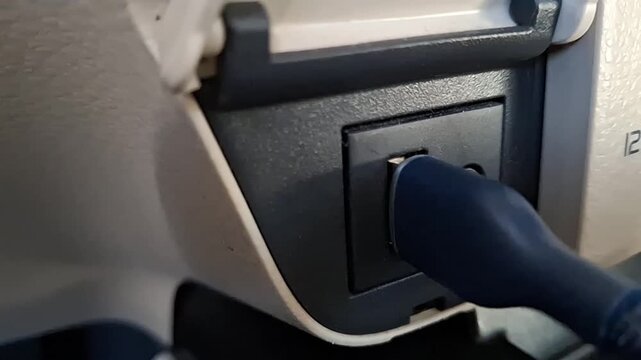 Close-up of inserting a USB cable into a car dashboard media port.