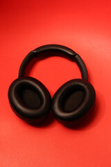 Black over-ear headphones with plush earcups resting on a vibrant red background