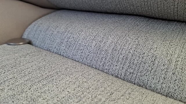 Close-up of Kuwaiti fils coins rolling and landing on a textured car seat.
