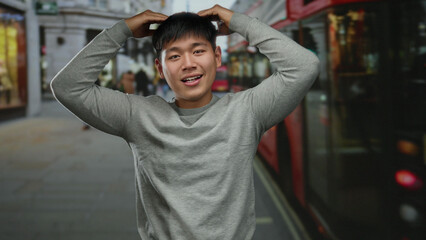 Obraz premium Young man posing playfully on a city street with a blurred urban background suggesting a lively and dynamic atmosphere complete with passing vehicles and architectural details.