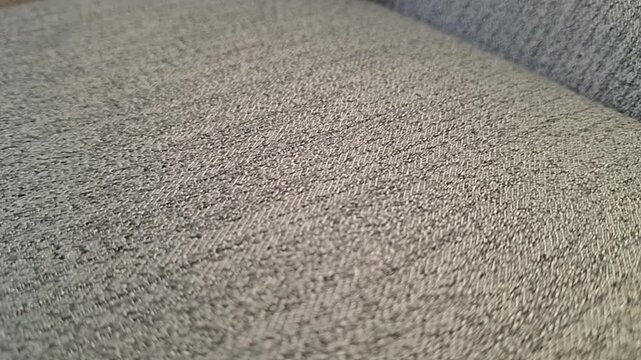 Close-up of Kuwaiti fils coins rolling and landing on a textured car seat.
