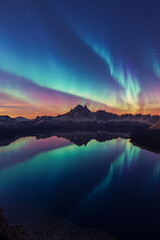 Aurora Borealis Over Snowy Mountains And Lake At Sunset Under Starry Sky