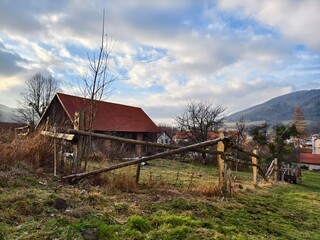small village house with a red roof and a wooden fence