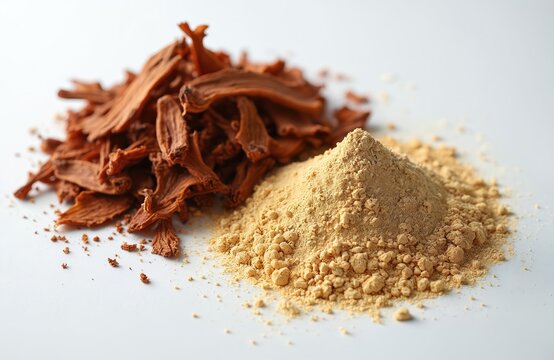 Pile of dried catuaba bark pieces next to a mound of fine yellow catuaba powder on a white surface. Natural herbal remedy from Amazon rainforest.