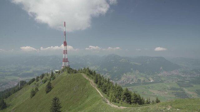 Towering red and white Sender Gr&uuml;nten radio mast on the green &Uuml;belhorn ridge in Allg&auml;u Alps. Scenic mountain panorama ideal for telecommunication and travel ads.