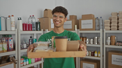 Man holds a tray of meals and a coffee cup while standing in a donation center building distributing donations; compassion community support.