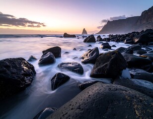 Obraz premium Ocean waves wash over a rocky beach with dramatic cliffs under a colorful sunset sky