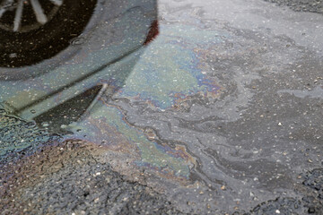 Naklejka premium Oil sheen rainbow pattern floating on puddle on asphalt road