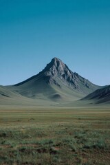 Fototapeta premium Solitary mountain peak standing proudly in vast green landscape