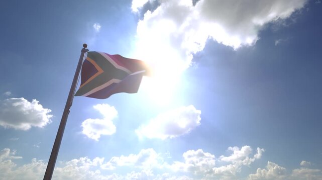 South Africa Flag waving on a Flagpole from a Moving Angle in front of a blue sky with clouds	