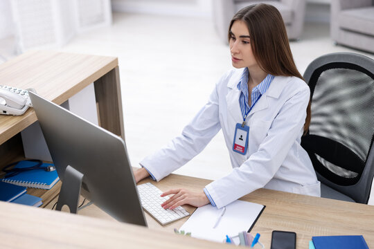 Medical assistant working on computer at reception in clinic