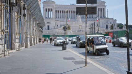 Blurred urban street with shallow bokeh showing distant monument, scaffolding and traffic, defocused foreground; background backdrop copyspace.
