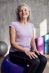 Obraz premium Senior woman smiling on fitness gym ball
