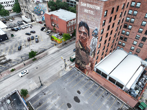 Aerial drone photo of the Assiduity mural on the Sam Houston Hotel in downtown Houston, Texas, dedicated to essential workers. Captured from above, this vibrant public artwork spans the side of the hi