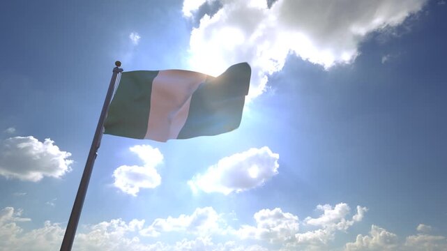 Nigeria Flag waving on a Flagpole from a Moving Angle in front of a blue sky with clouds	