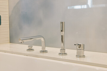 Faucet, sink and chrome bathroom fixtures arranged over a clean counter, water tap highlights...