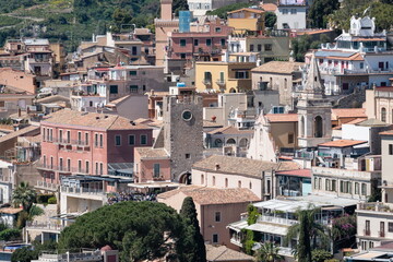 Obraz premium Taormina historic center with pastel houses, tiled rooftops, church bell tower and stone clock tower, Sicily Italy