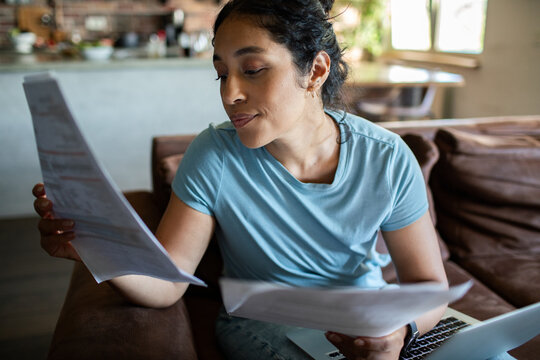 Woman reviewing household bills on couch at home