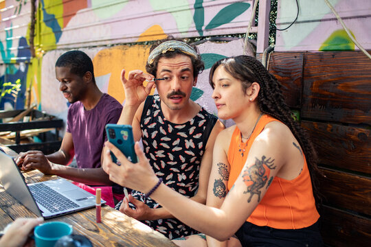 Friends applying makeup and working at an outdoor cafe