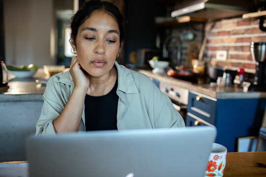 Pensive woman using laptop in home kitchen
