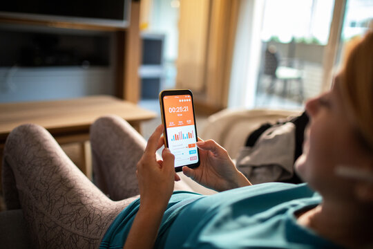 Woman checking fitness app on smartphone at home