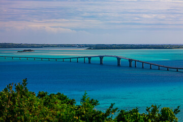 Fototapeta premium Irabu Bridge Over Clear Blue Sea Seen from Makiyama Observatory in Miyakojima 牧山展望台から望む伊良部大橋と宮古ブルーの海
