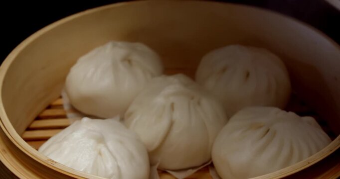 The delicious sight of freshly steamed white buns, rising in wisps of smoke, nestled in a traditional bamboo steamer, and the exquisite weaving of the steamer lid.