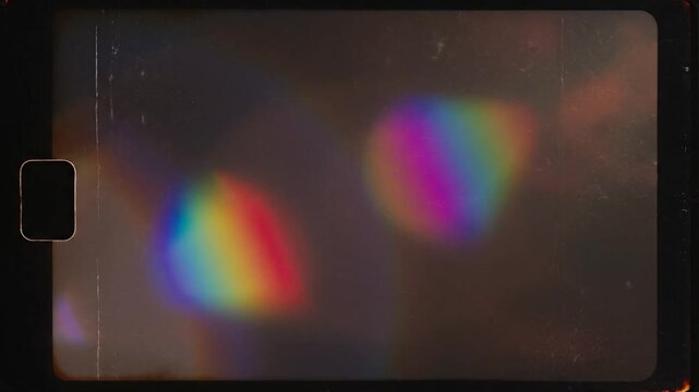 Abstract cinematic light leak overlay footage colorful rainbow light flares drifting slowly over deep black background vintage analog film burn look visible film grain dust scratches subtle flicker ex