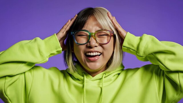 A shocked young Asian woman with vibrant split-dyed hair and neon rainbow glasses reacts dramatically against a solid purple background, expressing ex