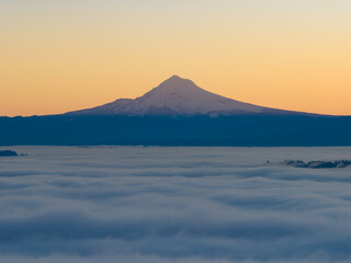 Dawn breaks on a blanket of fog surrounding Mount Hood, Oregon. This beautiful mountain and its surrounding national forest is near the city of Portland.
