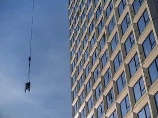 Obraz premium Tower crane lifting load at construction site, heavy equipment operation view
