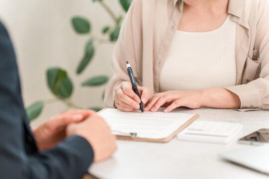 契約書,誓約書,書類にサインする女性客とビジネスマンの手元