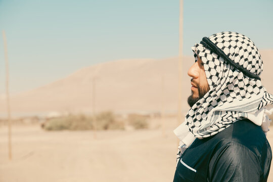 Arab man wearing keffiyeh and looking into distance in desert